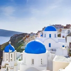 White buildings with blue domes overlooking the sea on a cliff