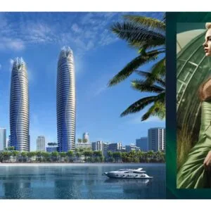 Two modern high-rise towers by waterfront with yachts and palm trees