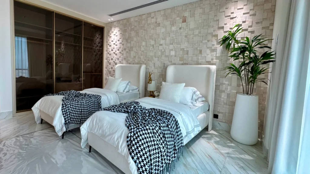 Twin beds with textured wall and plant in Al Fattan Marine Towers unit Dubai Marina Dubai