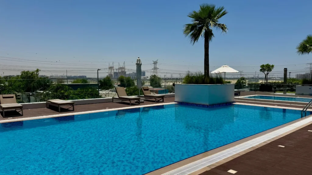 Бассейн с шезлонгами на территории Azizi Riviera 13 в районе Meydan Дубая
