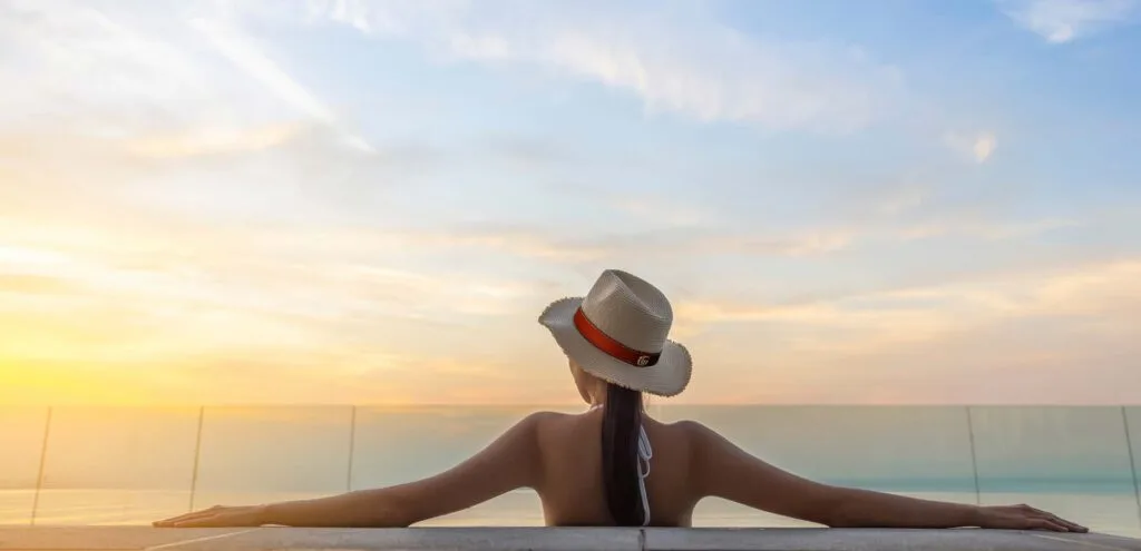 Person relaxing in rooftop infinity pool at sunset