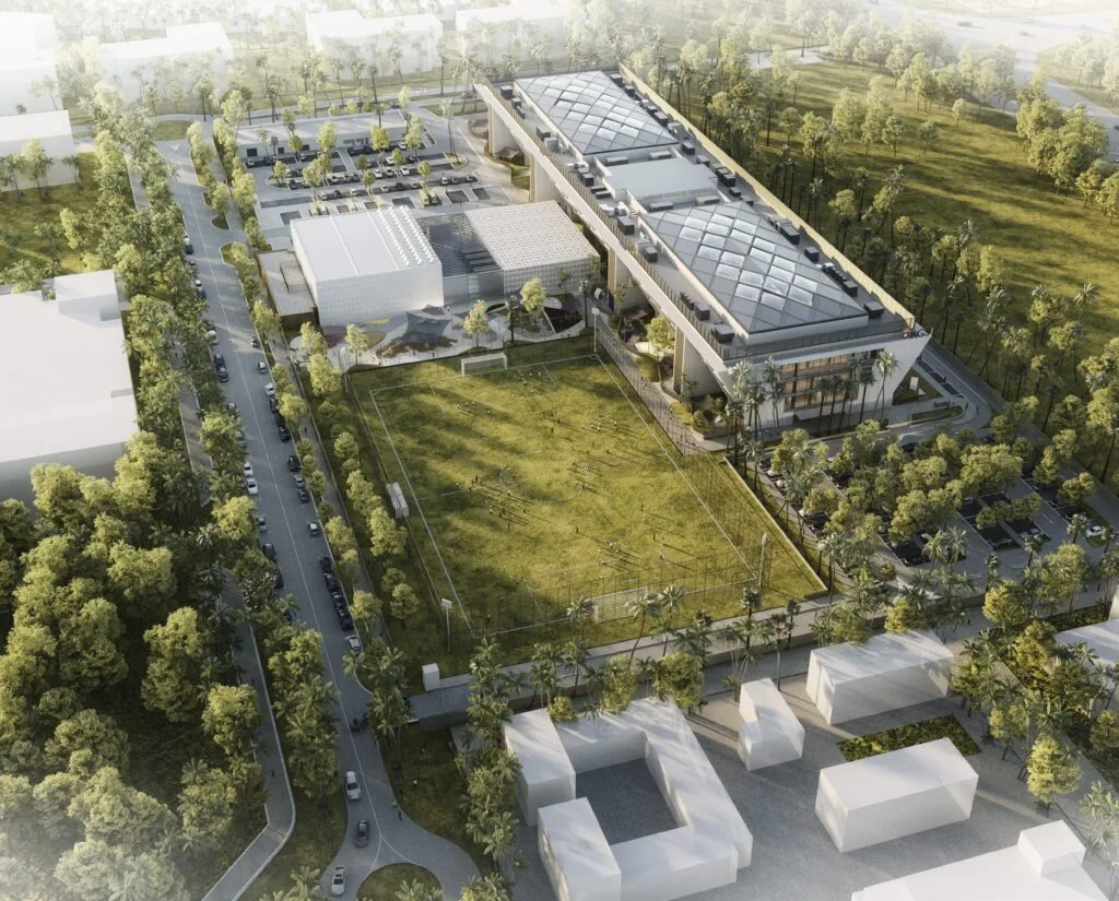 Aerial view of a large school building with sports field and surrounding trees