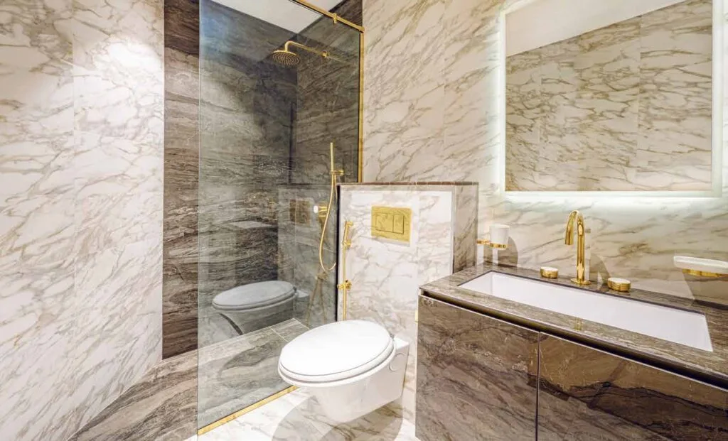 Bathroom interior with marble walls and gold fixtures