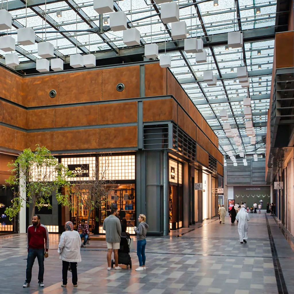 Covered City Walk pedestrian street with shops and visitors beneath a glass roof