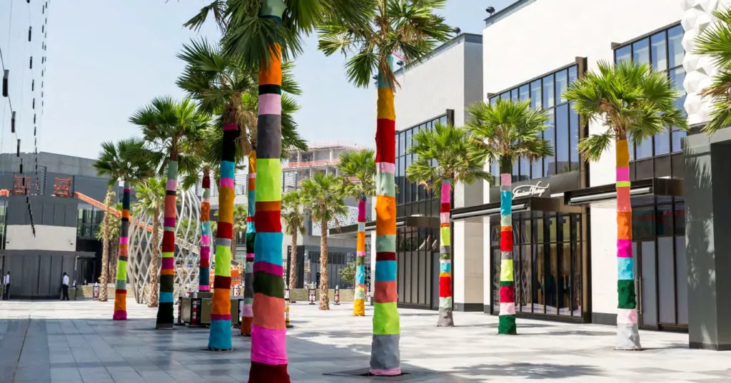 Palm-lined City Walk pedestrian street with colourfully wrapped trunks and shop frontage