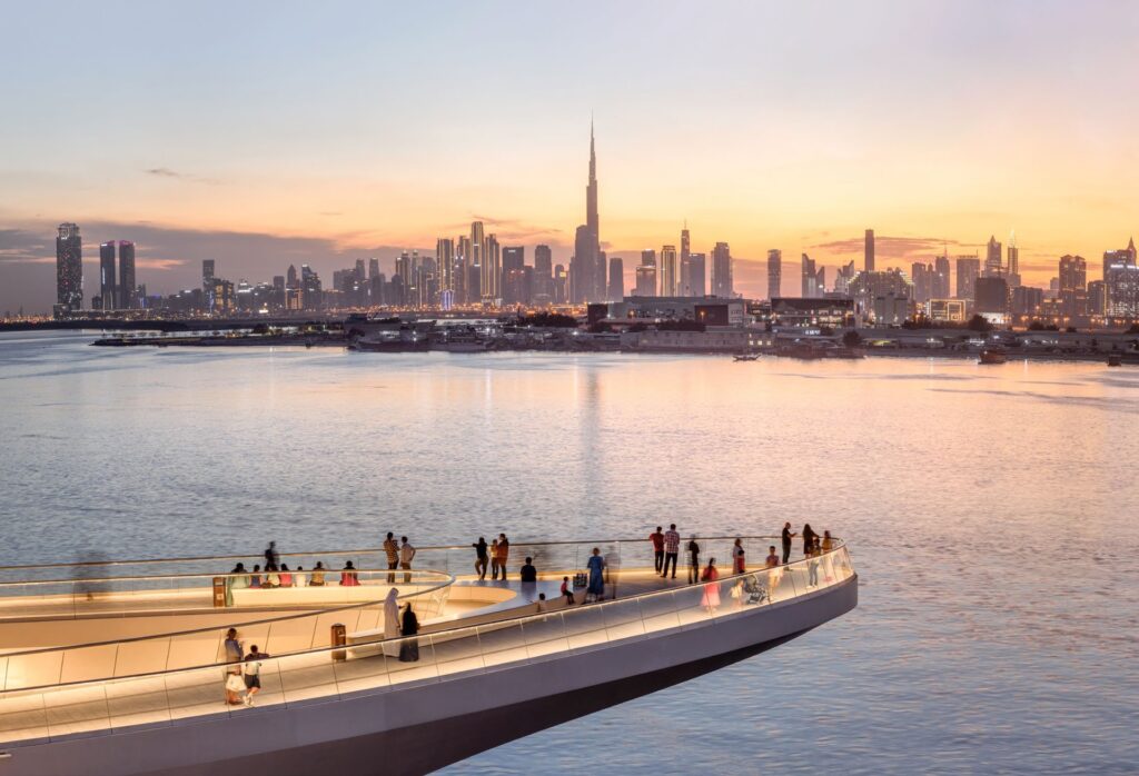 Waterfront view with people and Dubai city skyline at sunset