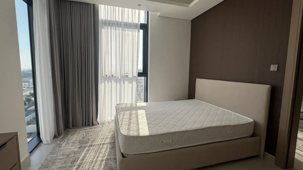 Спальня с кроватью и окнами в апартаментах Cloud Towers в Jumeirah Village Triangle Дубай