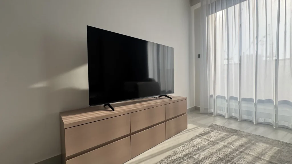 ТВ на комоде у окна с тюлевыми шторами в апартаментах Cloud Towers Jumeirah Village Triangle Dubai