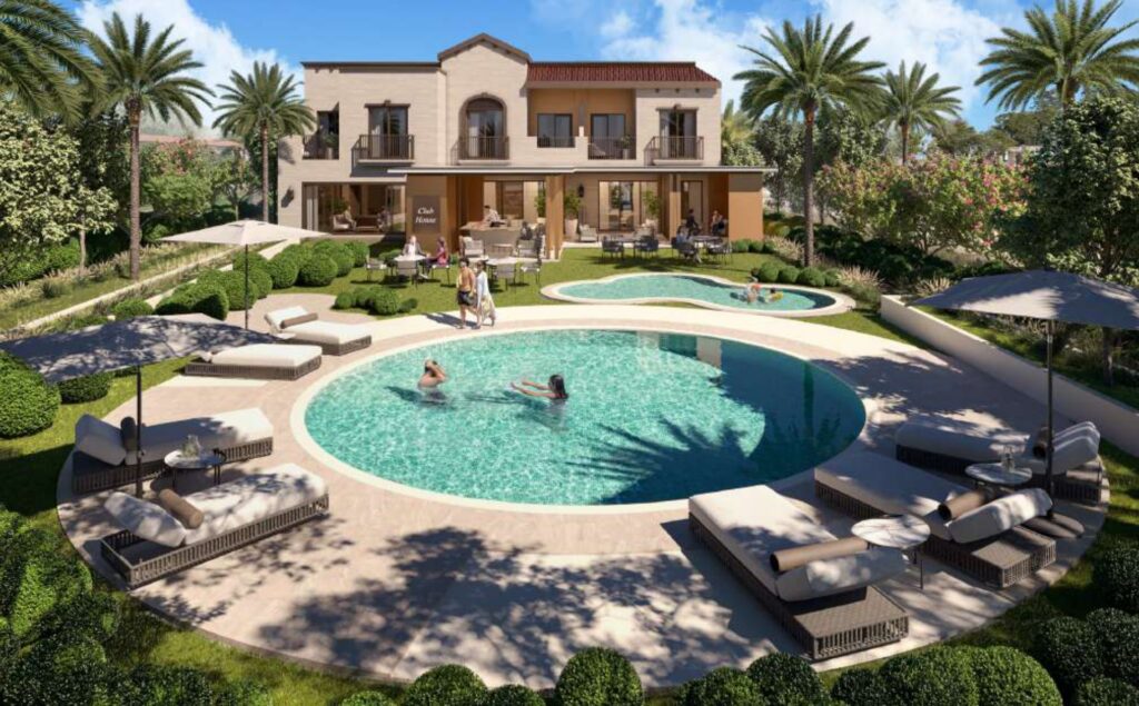 Two round swimming pools with sun loungers and a two-story building