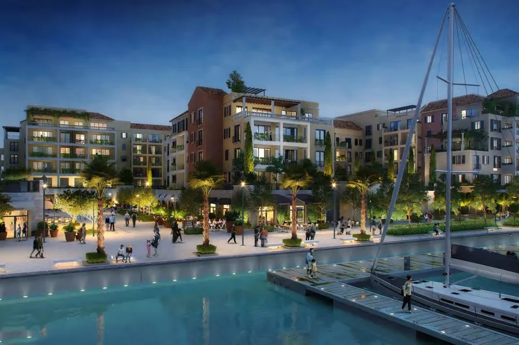 Marina docks with sailing yachts and illuminated waterfront buildings at dusk, Port de La Mer (developer rendering)