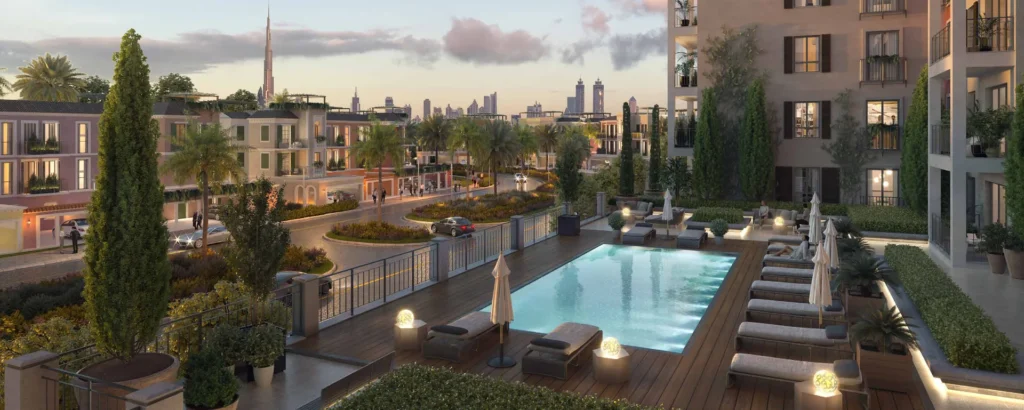 Pool terrace with sun loungers beside La Sirene apartment buildings at dusk (developer rendering)