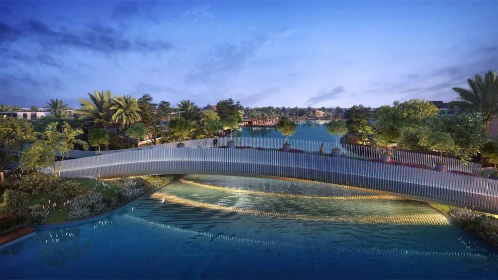 Curved pedestrian bridge over water with surrounding trees and buildings
