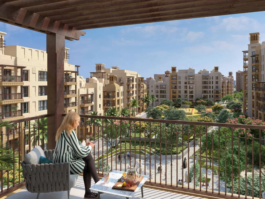 Al Jazi balcony view over landscaped residential courtyard with seating and Burj Al Arab beyond (developer rendering)