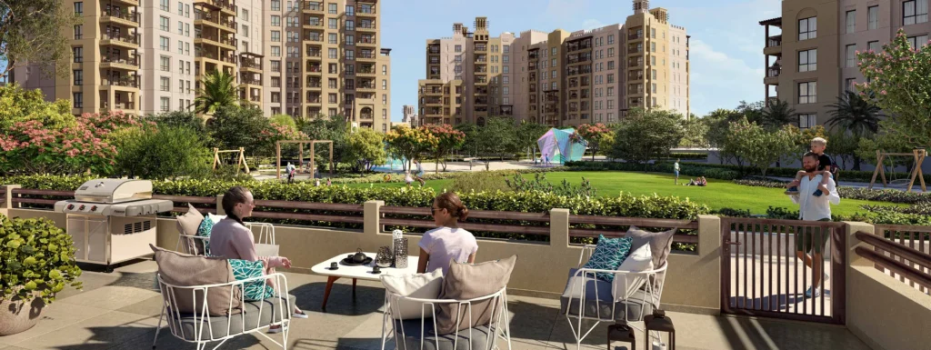 Residents on a landscaped terrace of Al Jazi with lawn and apartment buildings behind (developer rendering)