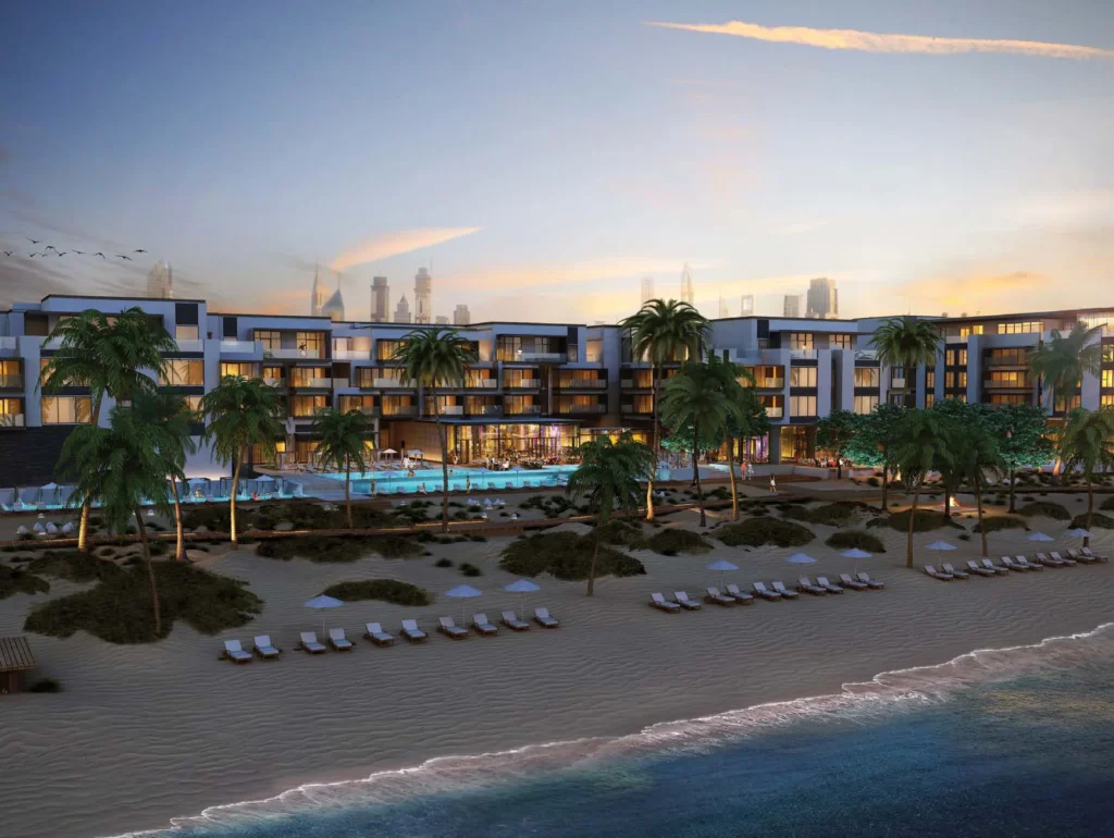 Nikki Beach Residences blocks around a pool with beach and Dubai skyline at dusk (developer rendering)