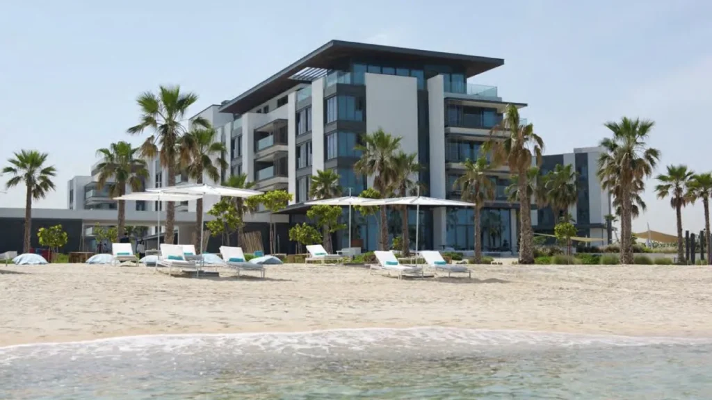 Nikki Beach Residences Dubai seen from the beach with palms and sun umbrellas