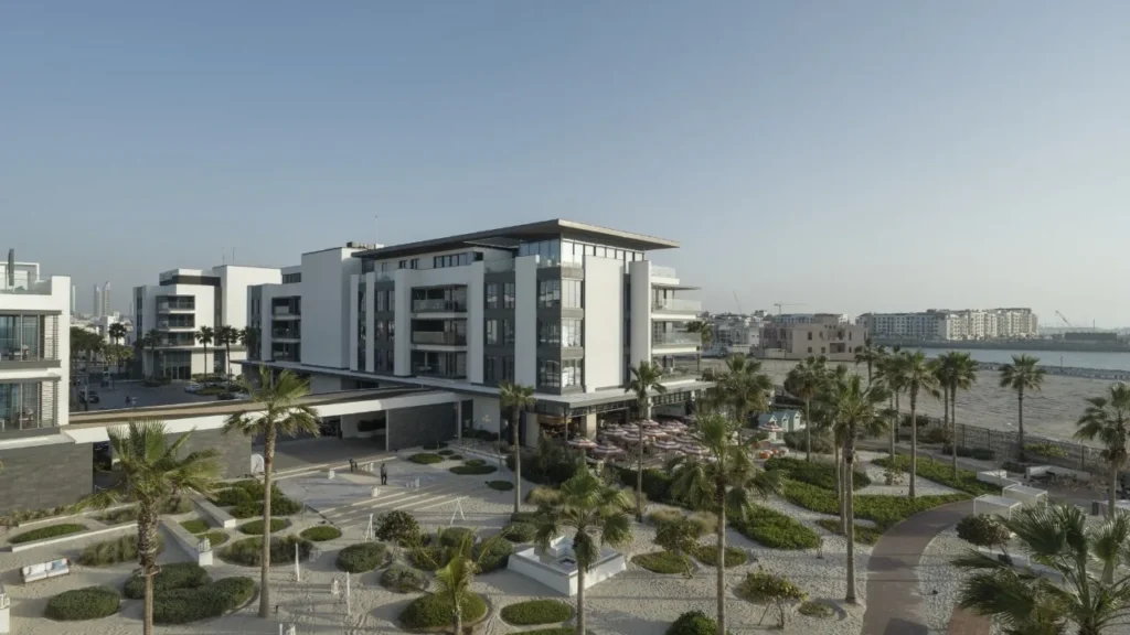 Nikki Beach Residences Dubai with palm-planted courtyard and Dubai skyline in the distance
