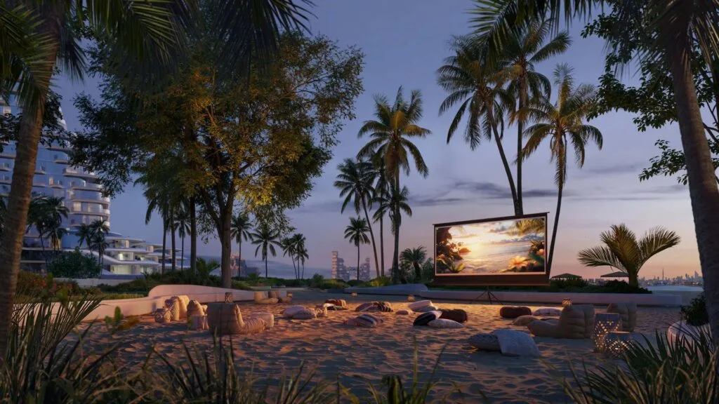 Outdoor seating area with large screen and palm trees at dusk