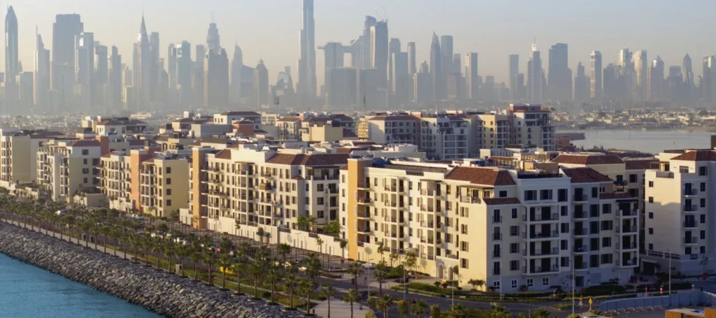Port de La Mer waterfront apartment buildings along the marina with the Dubai skyline behind (developer rendering)