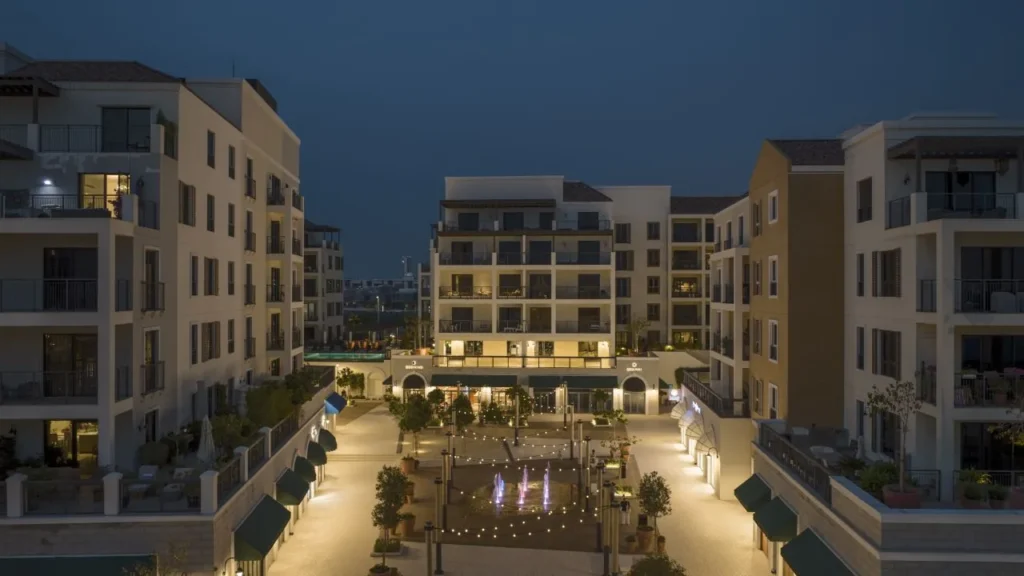 Port de La Mer residential courtyard with illuminated plaza and apartment buildings at night (developer rendering)