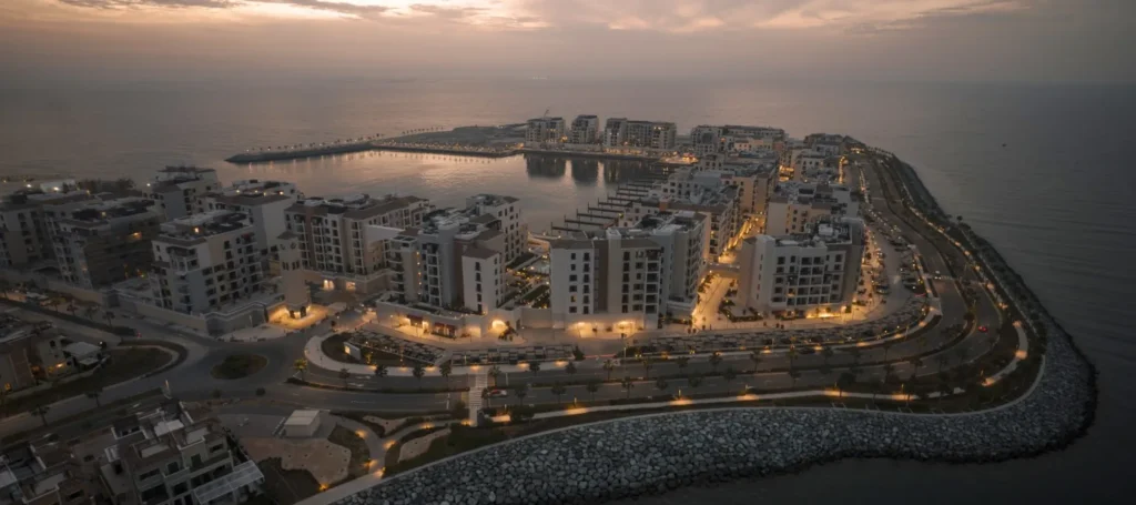 Port de La Mer island aerial at dusk with illuminated buildings along the shoreline (developer rendering)