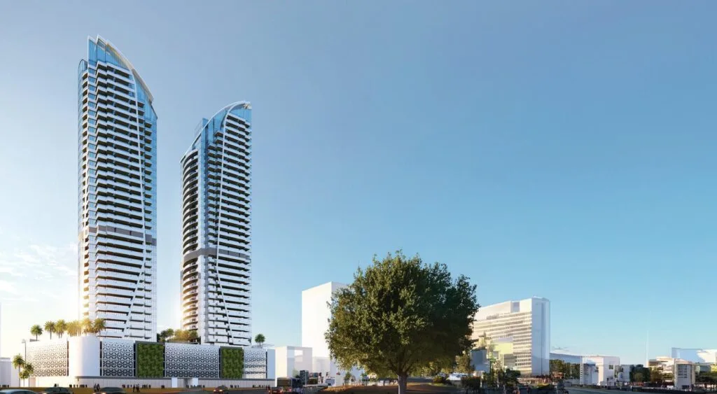 Two tall modern residential towers with surrounding low-rise buildings