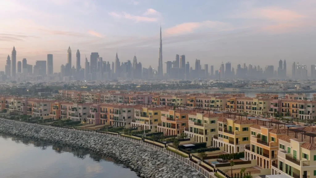 Sur La Mer townhouses in Mediterranean colours along the rocky waterfront with the Dubai skyline behind