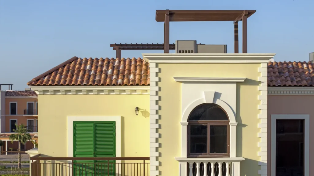 Yellow Sur La Mer townhouse with arched window, green shutters and rooftop pergola