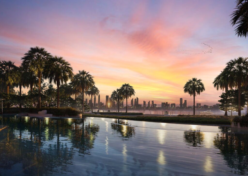 Pool with palm trees and city skyline at sunset