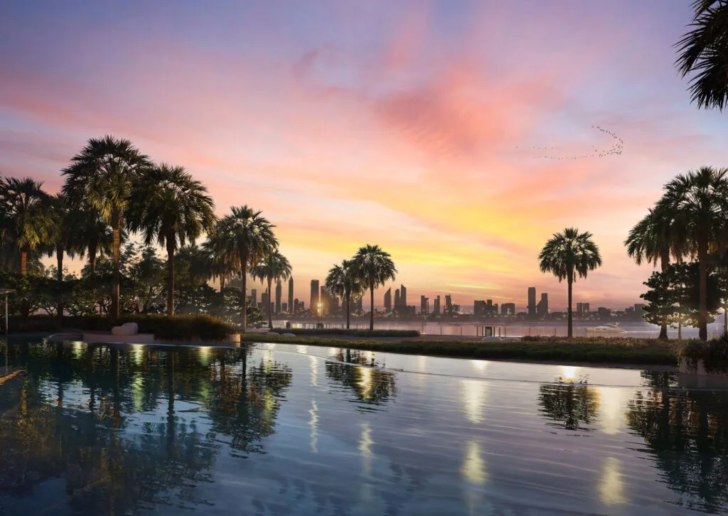 Pool with palm trees and city skyline at sunset